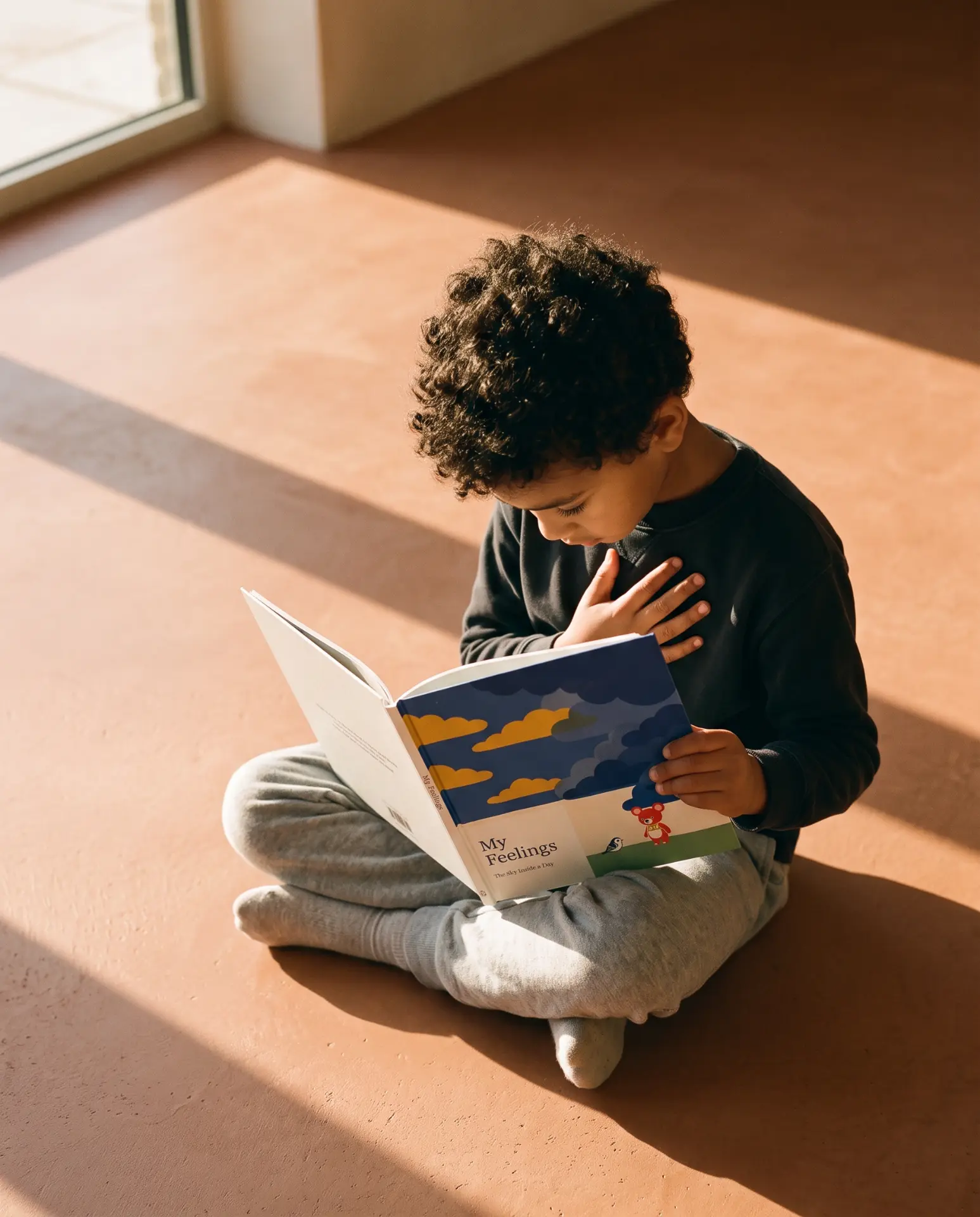 A child reading a feelings book with one hand on their heart